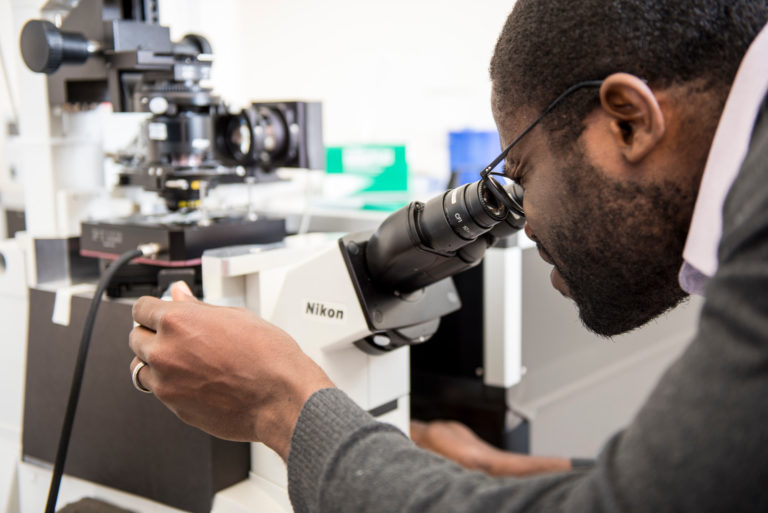 UW researcher looking through microscope