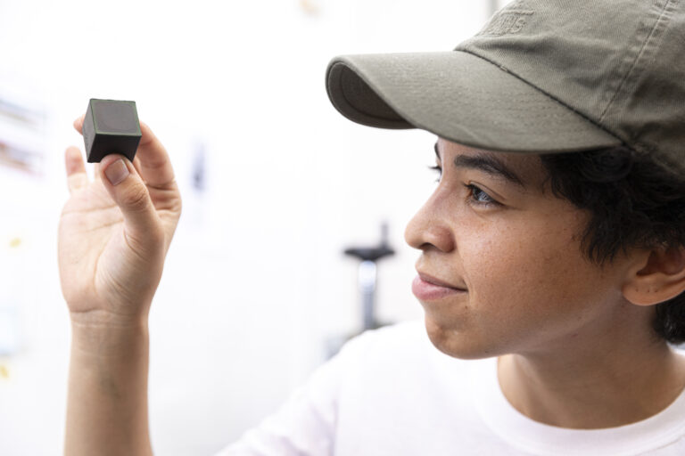Mallory Parker, UW materials science and engineering doctoral student, holds up a bioplastic cube made from spirulina