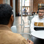 two people with headphones seated at table