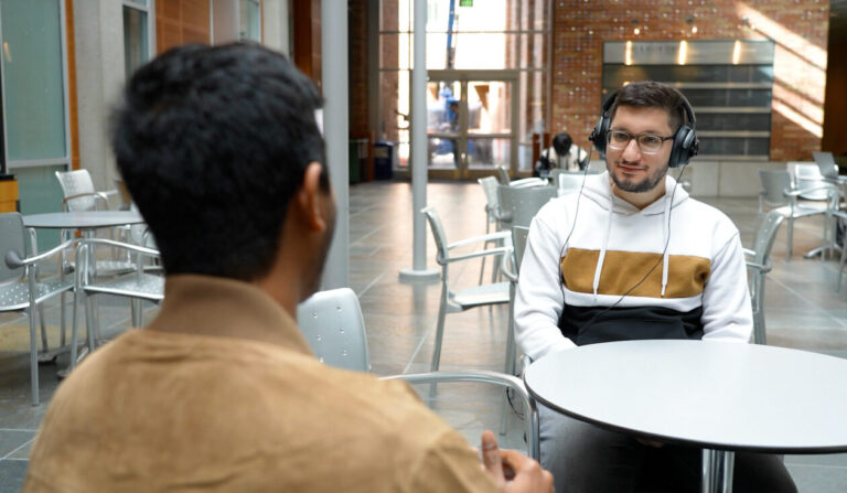 two people with headphones seated at table