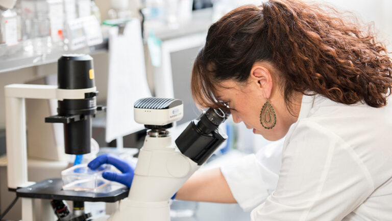 Researcher looking into microscope.