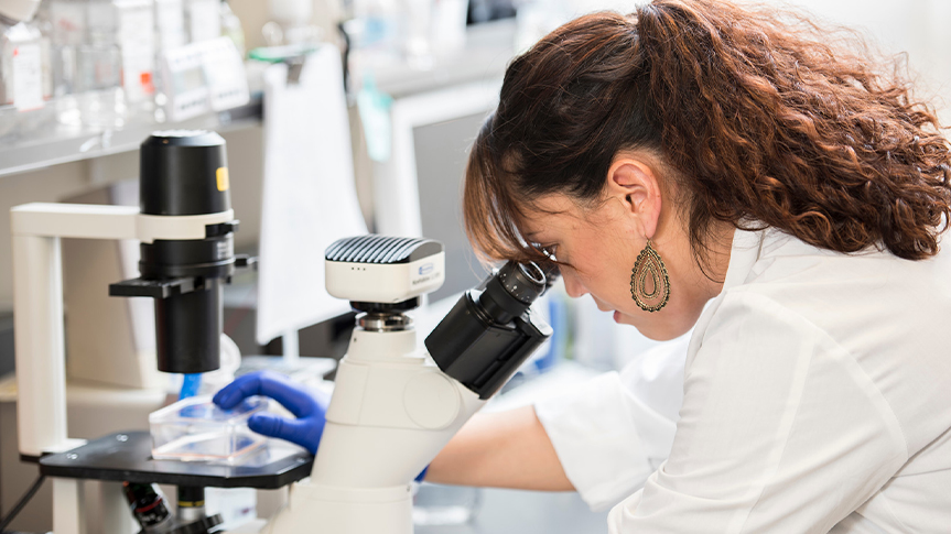 Researcher looking into microscope.