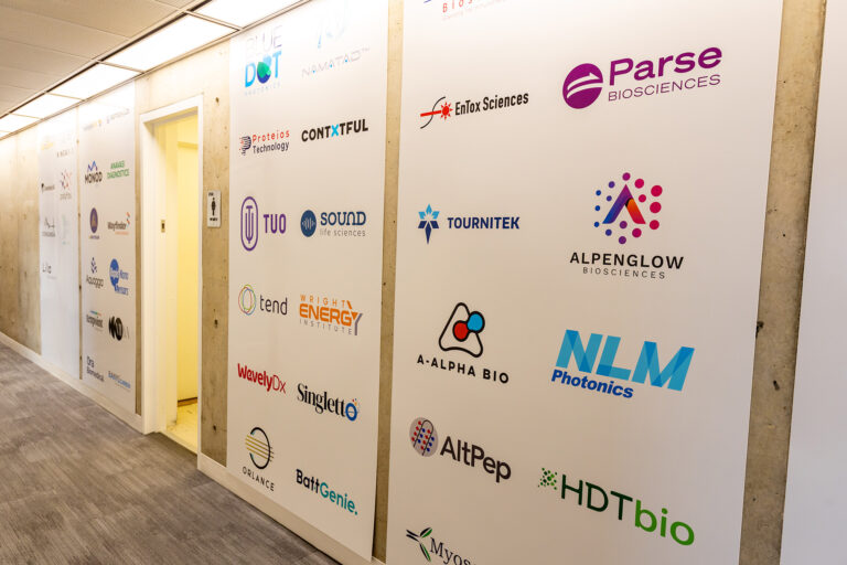 CoMotion HQ startup logo wall with Parse Biosciences, A-Alpha Bio, AltPep, BlueDot Photonics, Proteios Technology and NLM Photonics visible