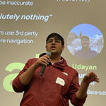 A student making a presentation in front of a powerpoint slide.